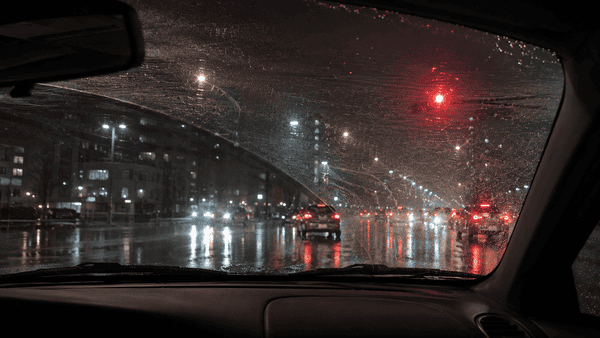 Windshield scratches and wiper marks causing glare and blurred vision while driving at night in the rain